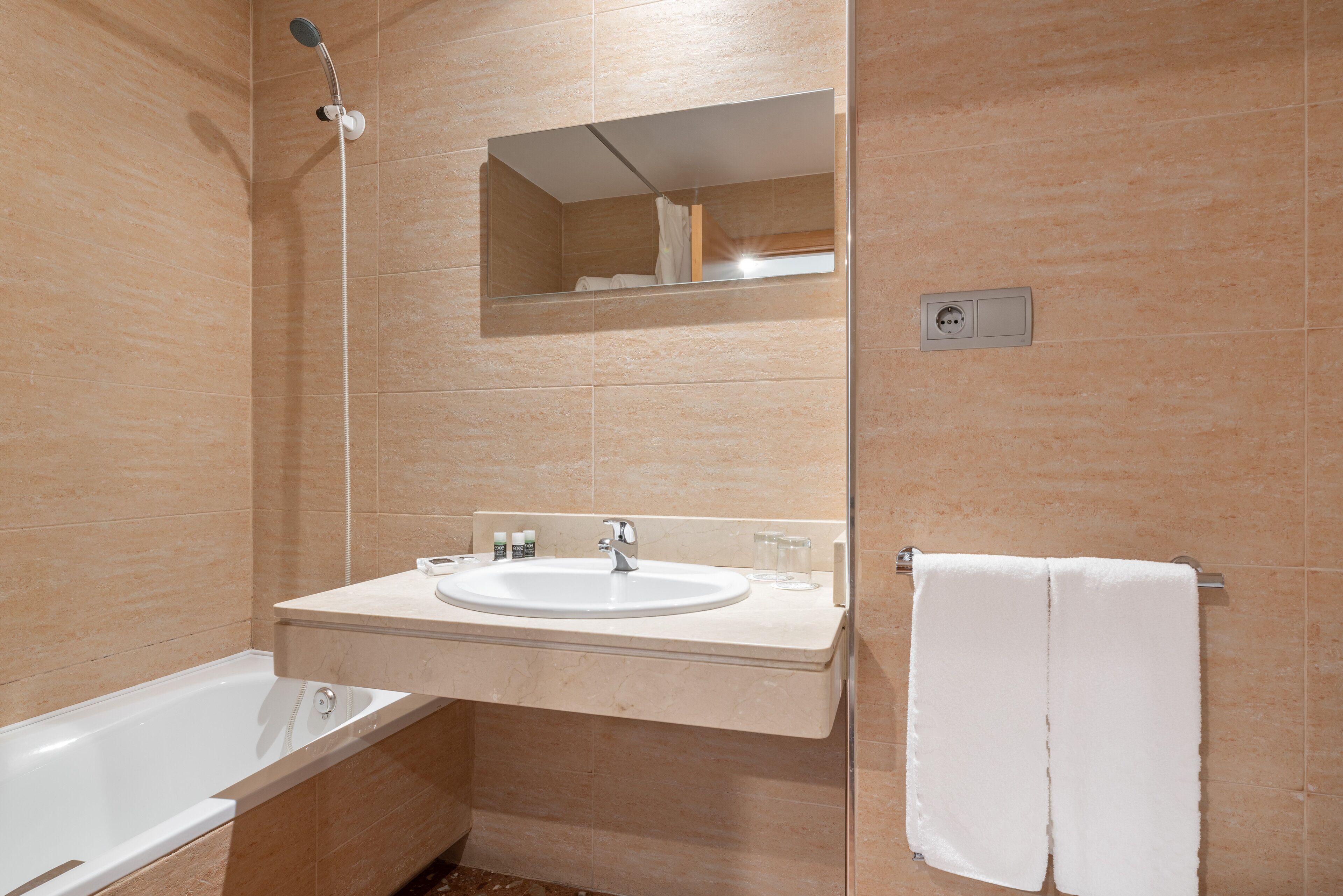 Un baño con bañera, lavamanos y espejo sobre el lavamanos.