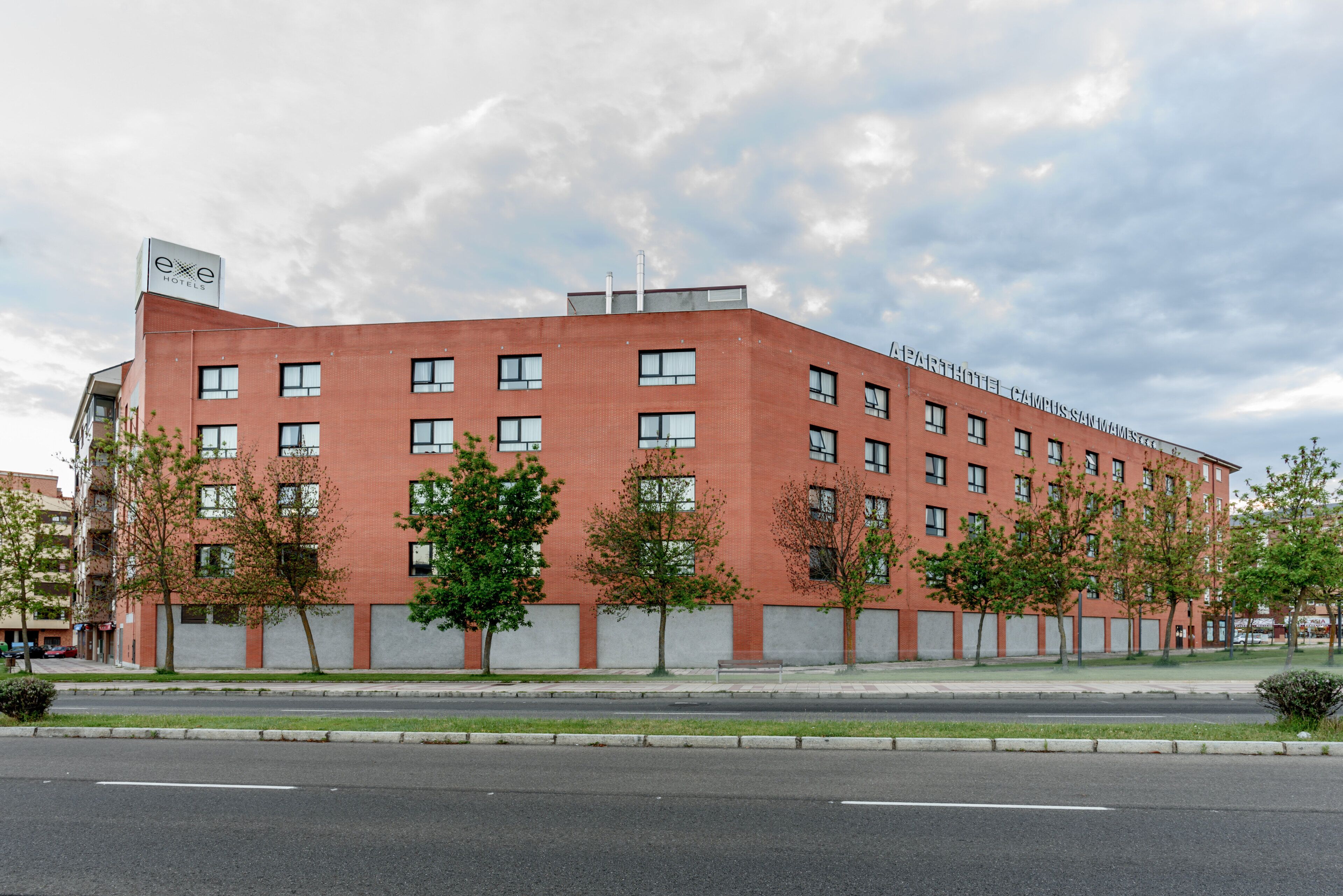 A red-brick building with multiple windows and a sign for 'Exxe Hotels'.