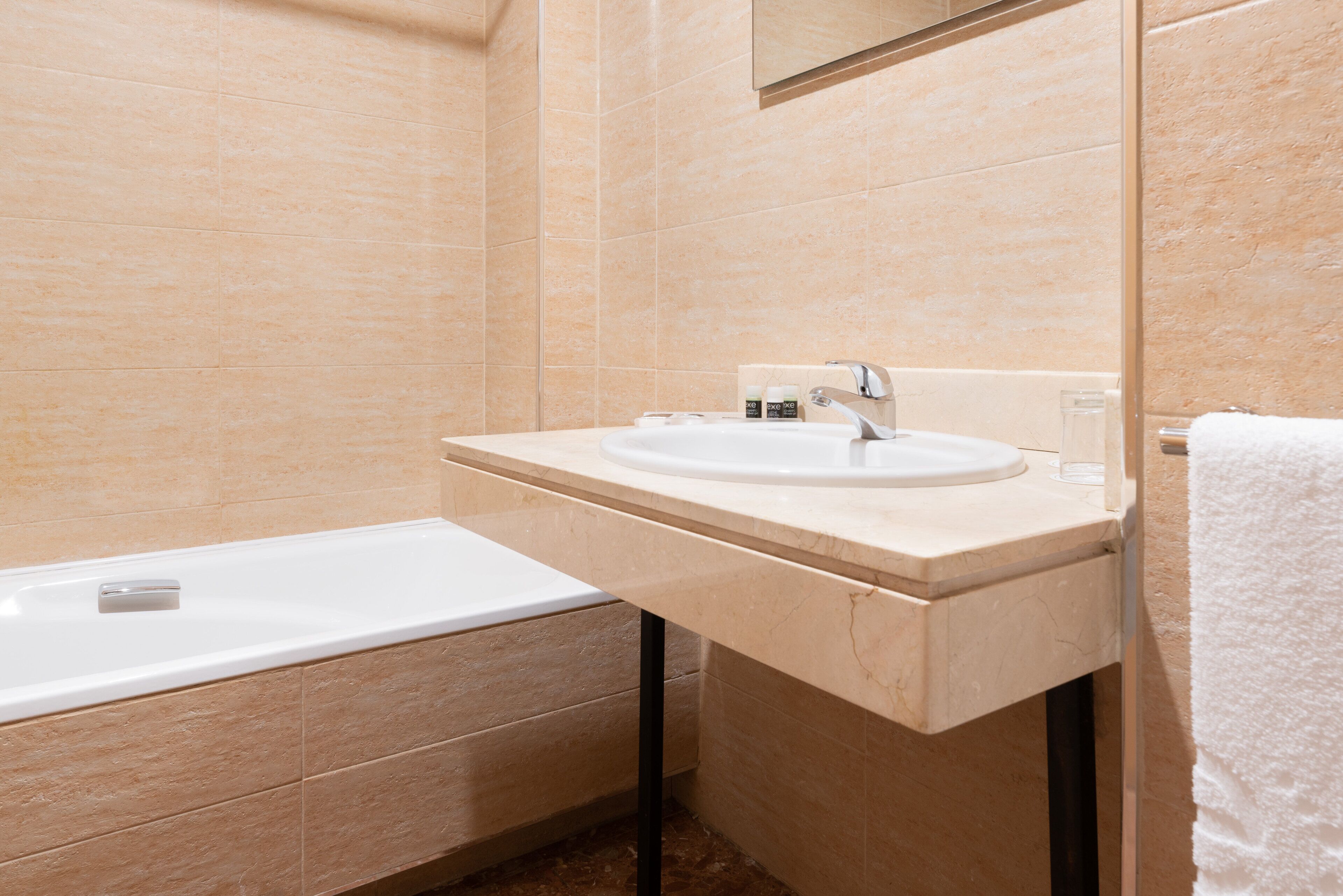 A modern bathroom with a bathtub, a sink, and a mirror.
