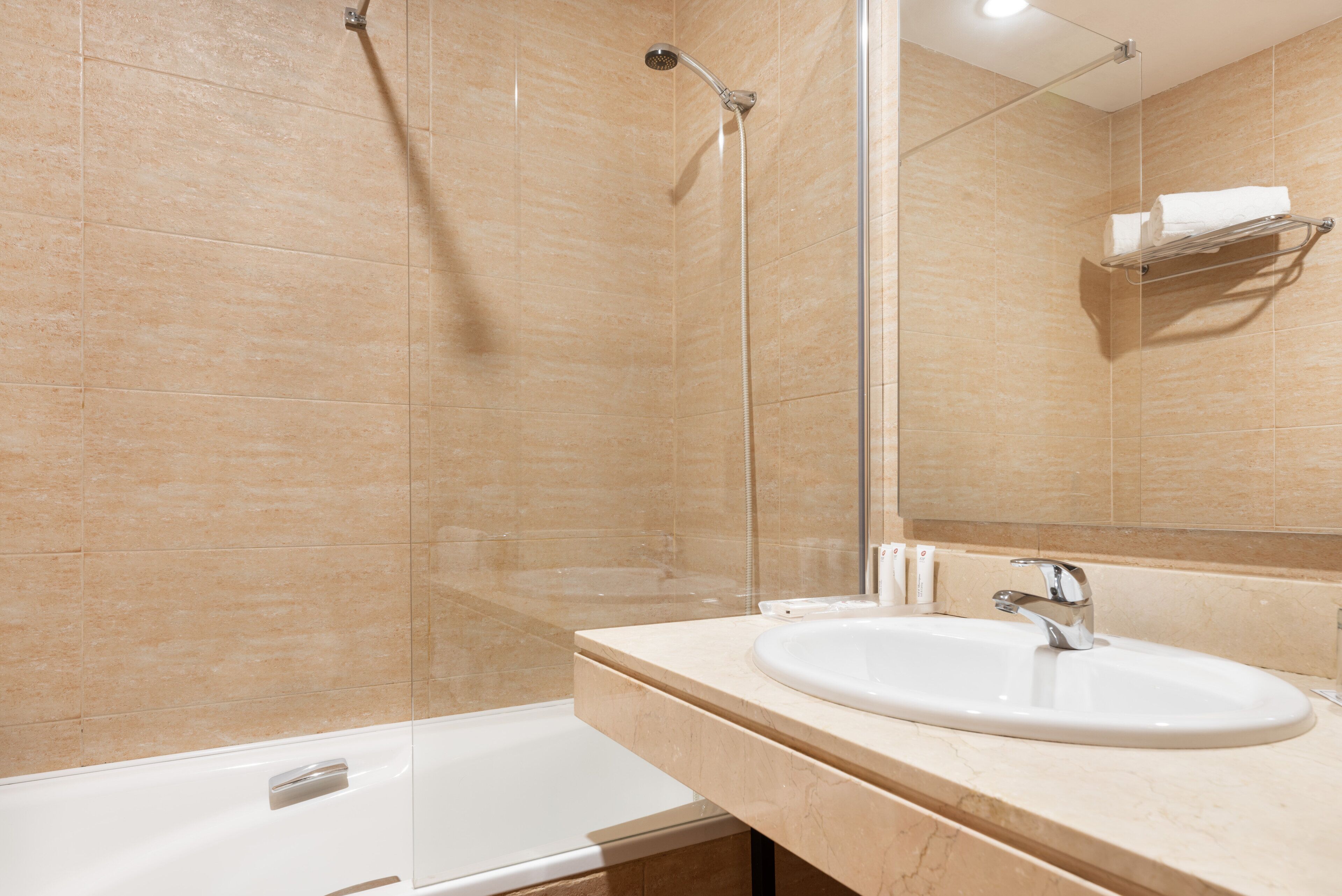Un bagno moderno con doccia vetrata, vasca da bagno bianca e lavandino con specchio sopra.