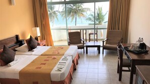 A hotel room with two beds, a small table, a chair, and a view of the ocean.