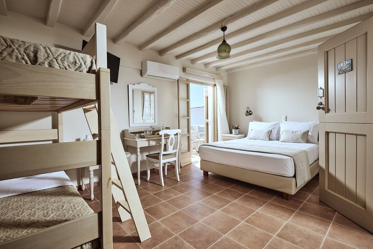 A bedroom with a bunk bed, a desk, a chair, and a bed.