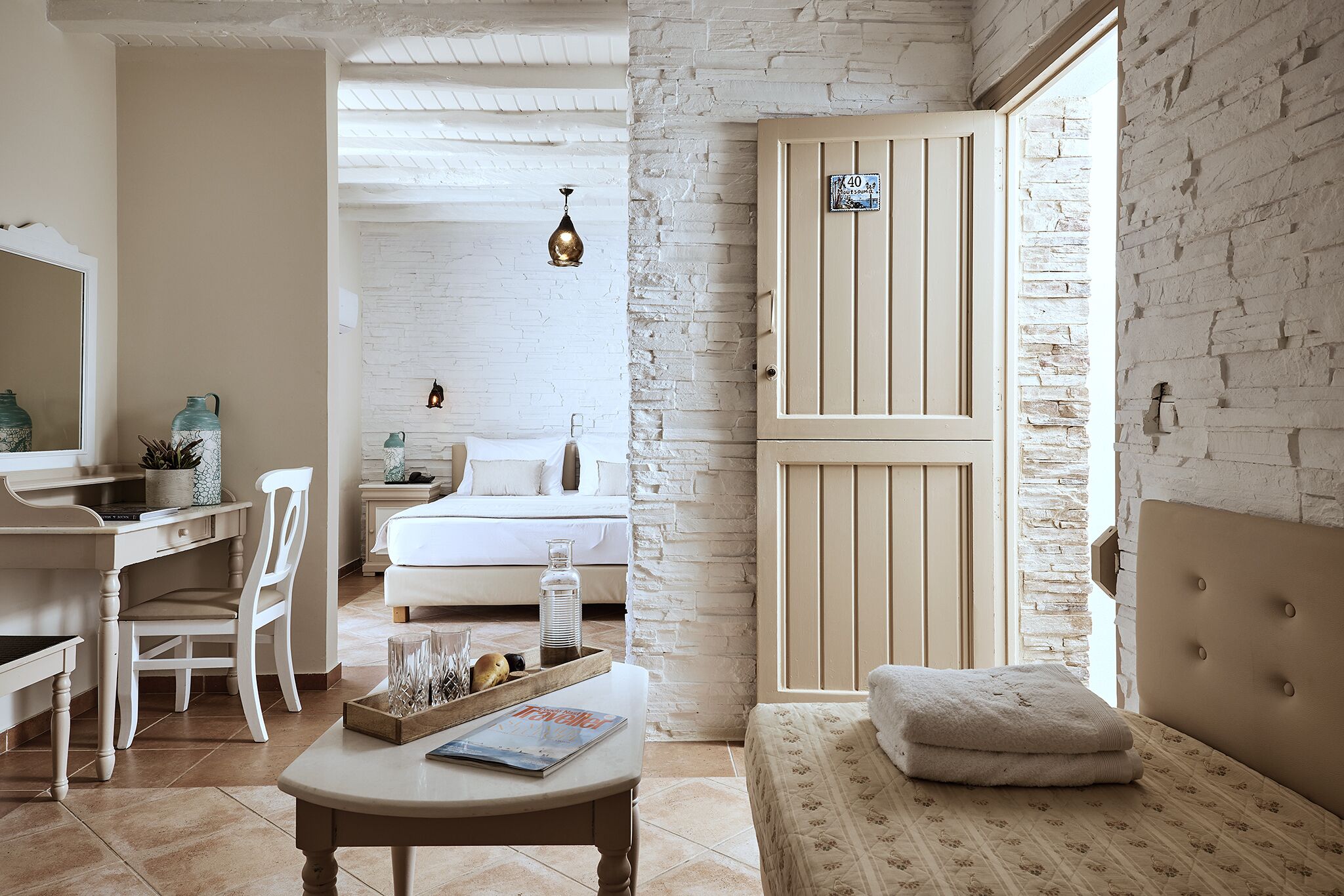 A bedroom with a bed, a bedside table, a chair, a desk, and a window.
