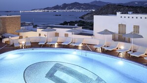 A rooftop pool with lounge chairs and umbrellas, overlooking a coastal town and mountains. - Naxos Magic Village Hotel (Naxos)