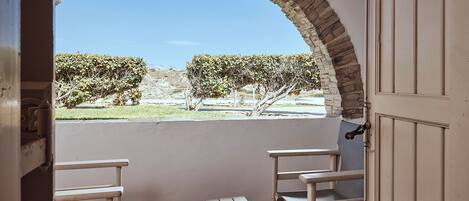 Un espacio al aire libre con zona de estar y vistas a través de un arco, que incluye una mesa pequeña y dos sillas.
