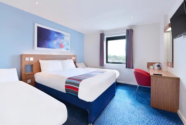 A hotel room with a bed, a desk, a chair, a TV, and a window with curtains. - Travelodge Inverness Fairways (Inverness)
