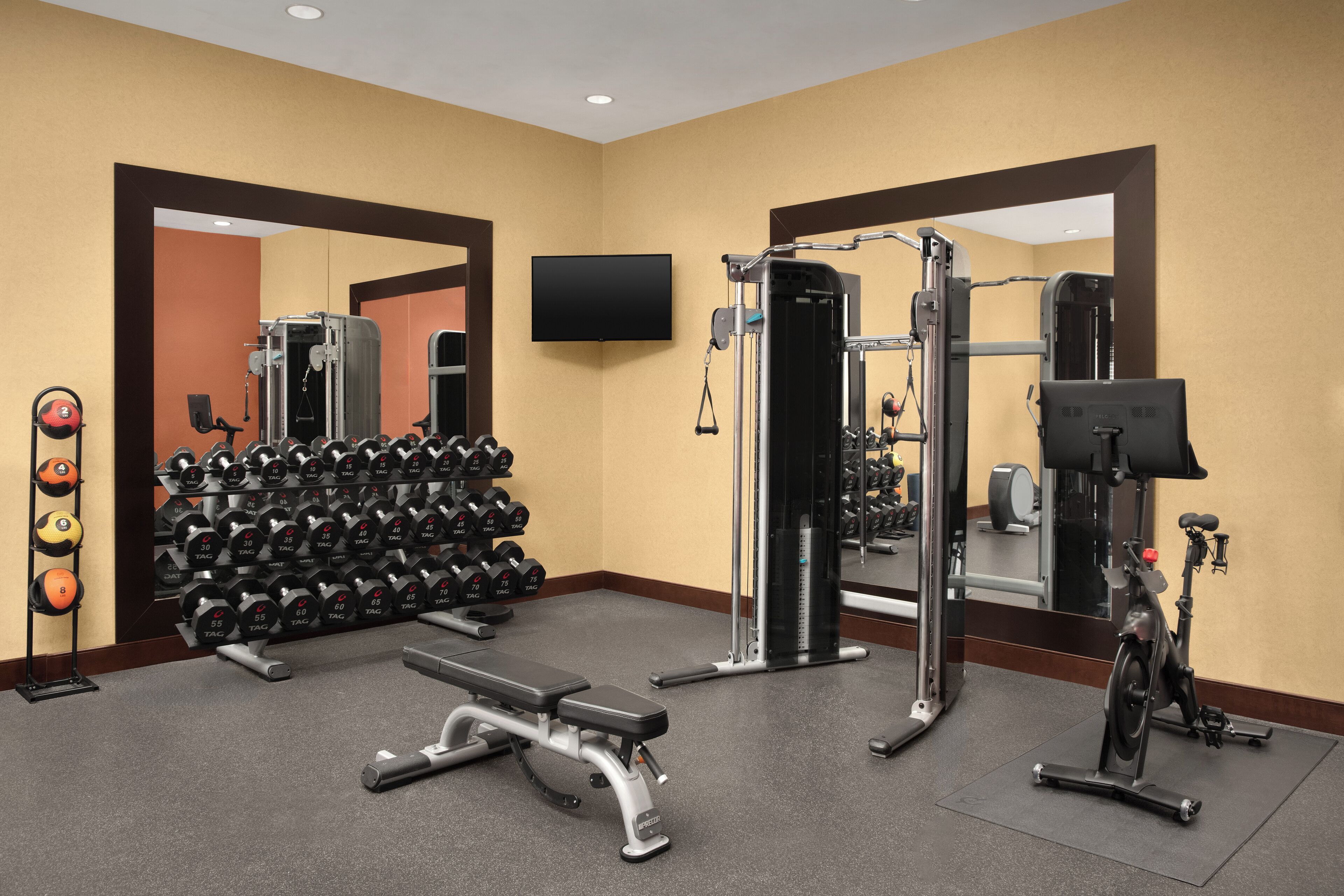 A gym with weightlifting equipment, dumbbells, and exercise machines.