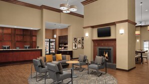 Eine Hotte Lobby mit Bar, Sitzgelegenheiten, Kamin und einem an der Wand befestigten Fernseher.