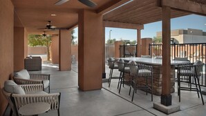 Ein Terrassenbereich im Freien mit Deckenventilatoren, Korbmöbeln und einer Bar.