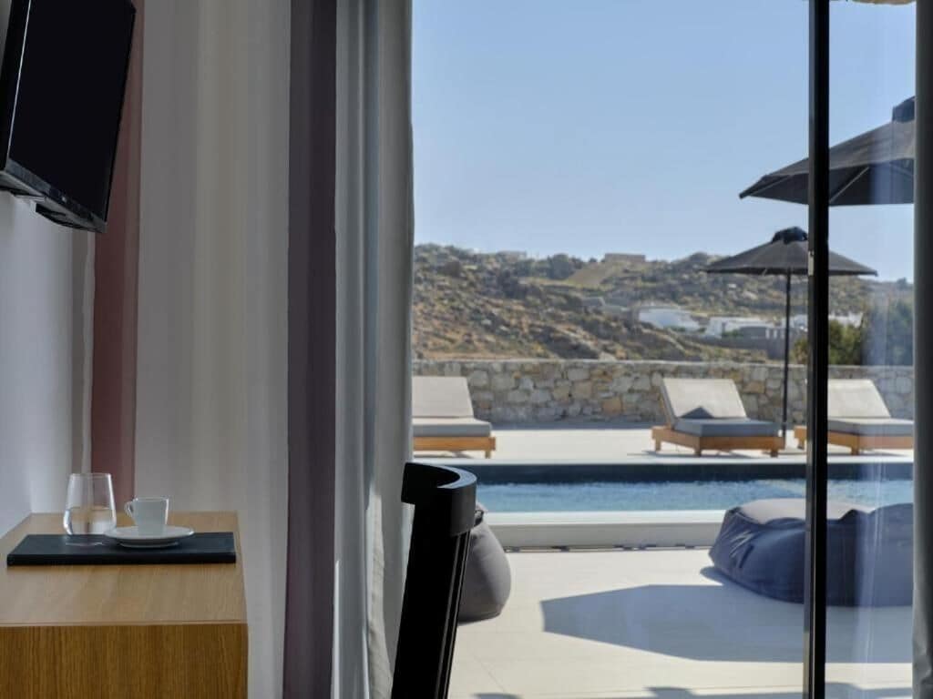 A modern room with a large window overlooking a pool and lounge area.
