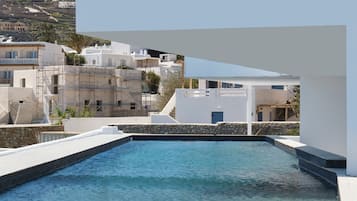 A pool with clear water, surrounded by white buildings and a stone wall.