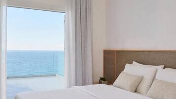 A hotel room with a large bed, a view of the sea, and a balcony.