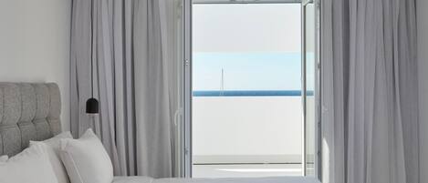 Una habitación de hotel con cama, cortinas y vista al mar.