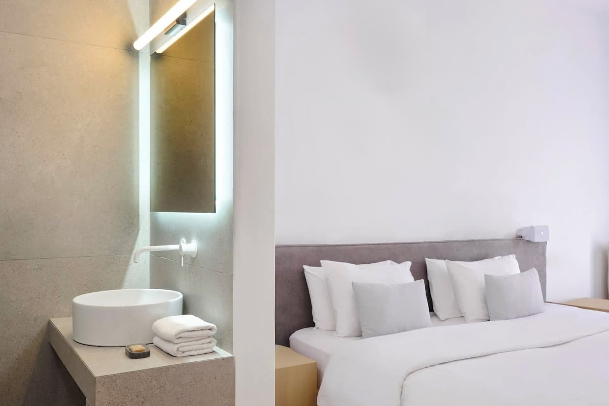 A modern bathroom with a round sink, a towel stack, and a mirror.