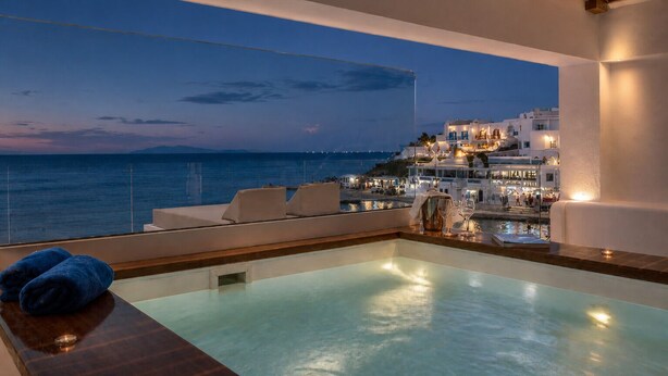 Una piscina infinita en la azotea con vistas a un pueblo costero al atardecer.