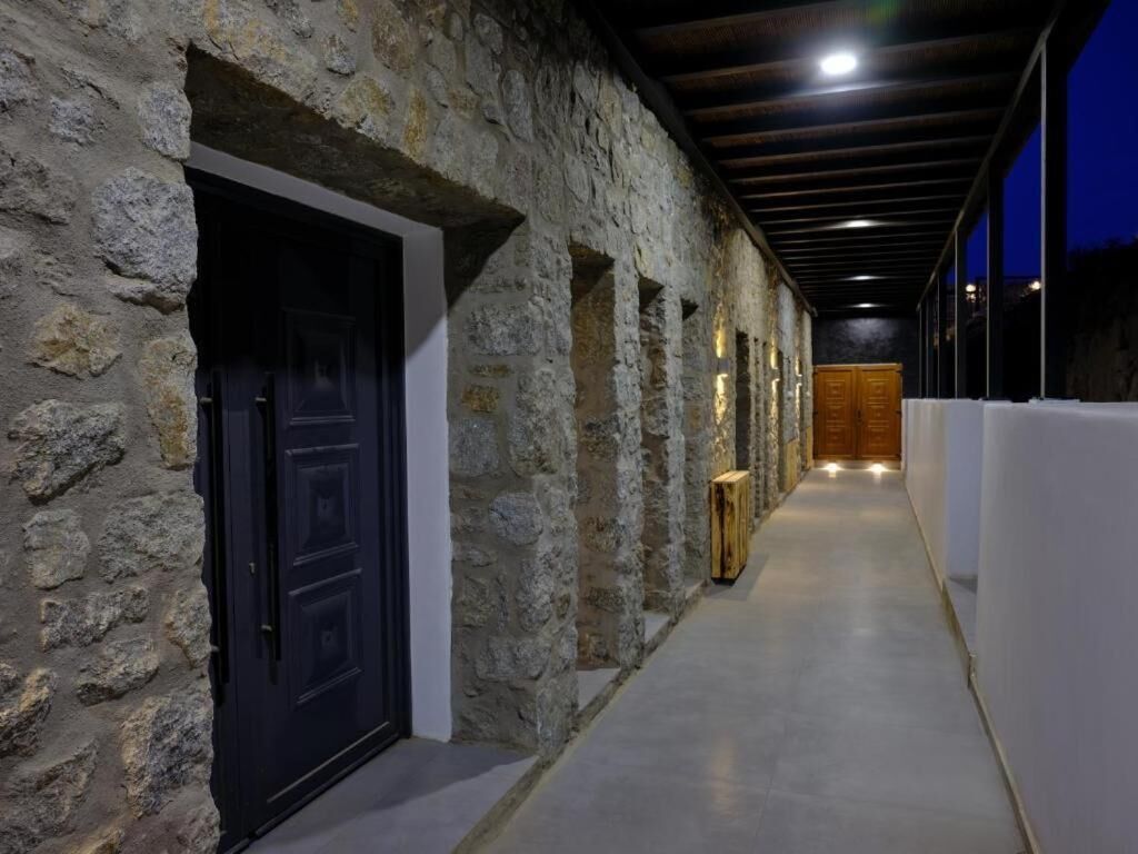 A corridor with stone walls, wooden doors, and a wooden panel wall at the end.