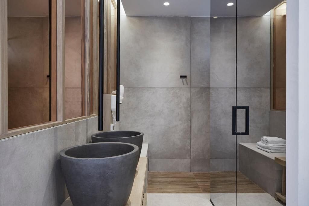 A modern bathroom with a large mirror, a shower area, and a wooden vanity.