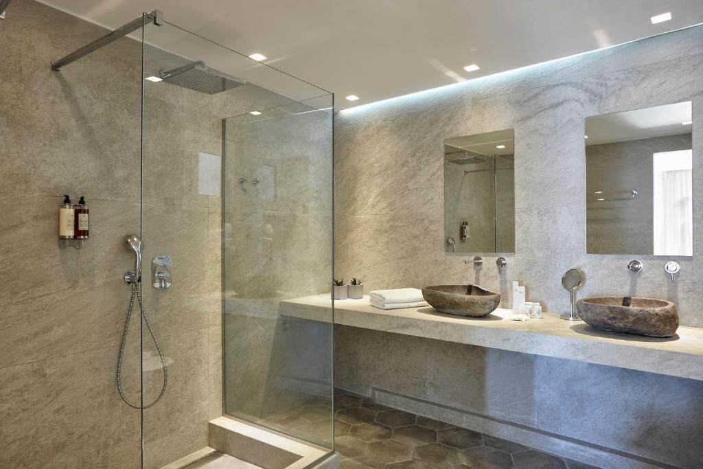 A modern bathroom with a glass-enclosed shower, a marble countertop, and a large mirror.