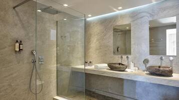 A modern bathroom with a glass-enclosed shower, a marble countertop, and a large mirror.
