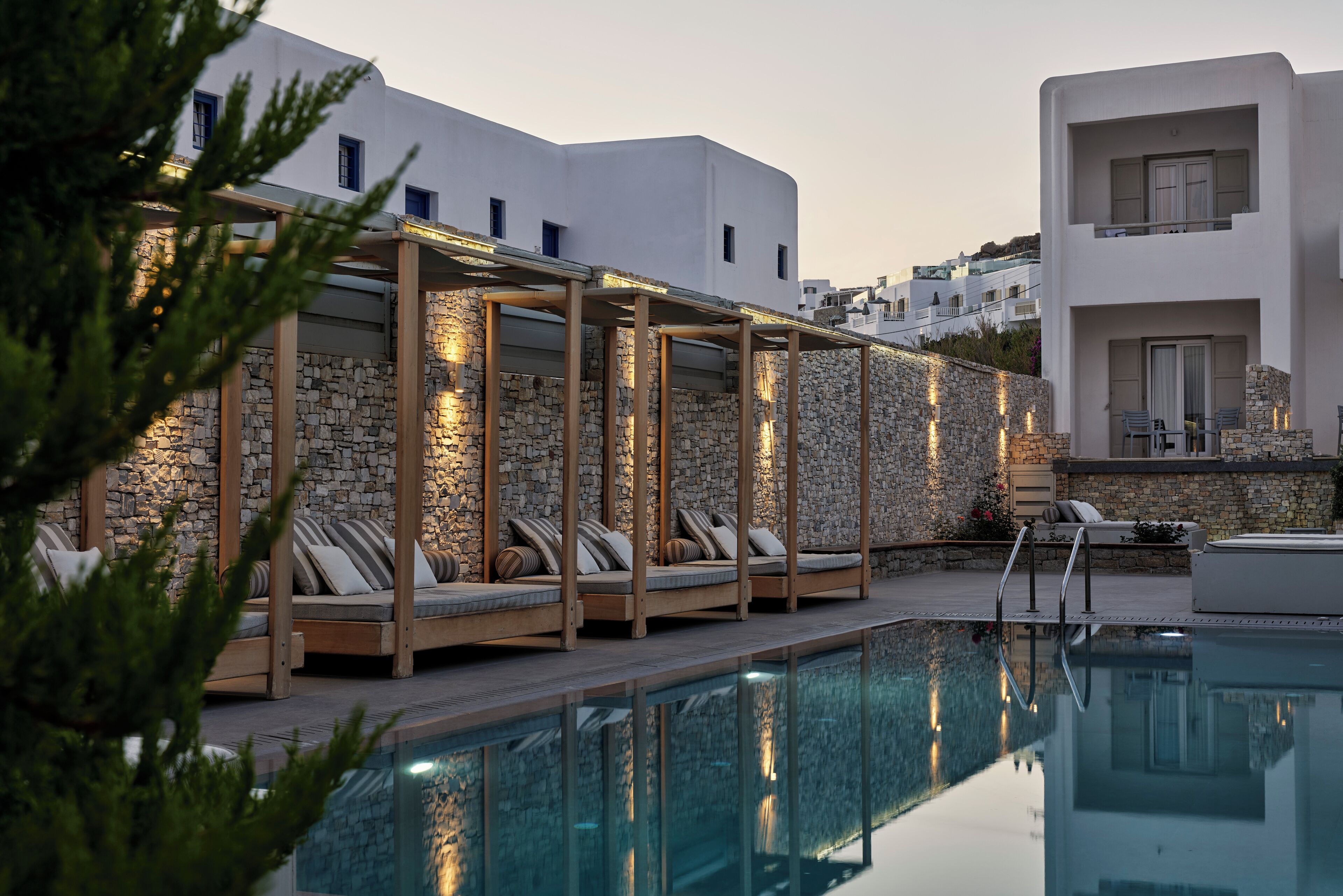 A poolside area with lounge chairs and a stone wall.