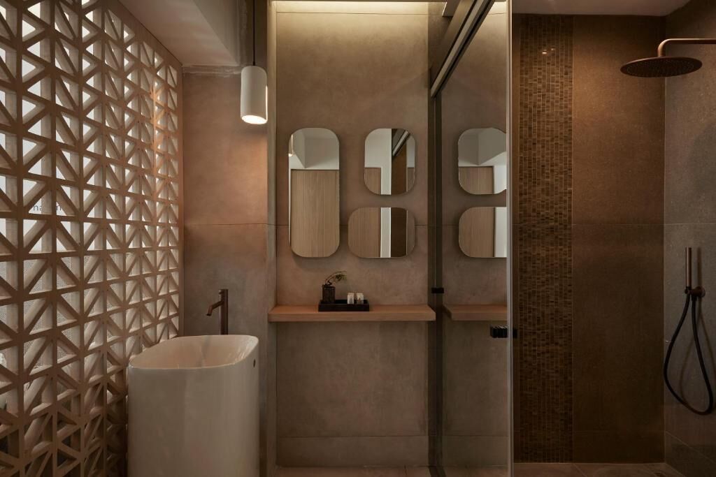 A modern bathroom with a geometric wall design, a sink with mirrors, and a shower area.