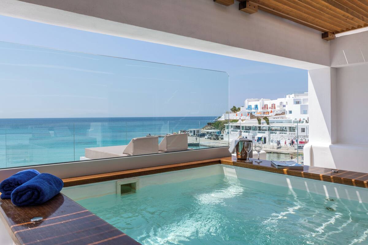A modern infinity pool with a clear view of the ocean and coastal buildings.