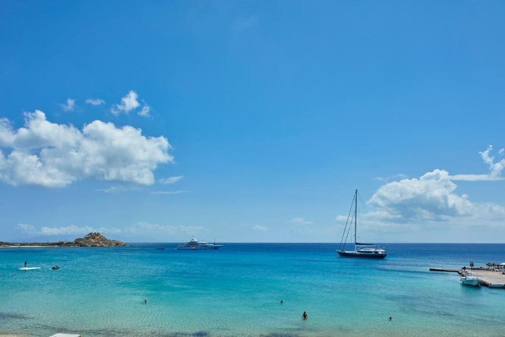 A coastal scene with clear turquoise waters, a rocky island, and several boats.