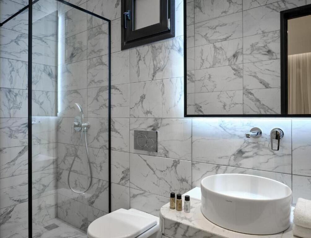 Une salle de bain moderne avec une douche à parois de verre, des toilettes blanches et un grand lavabo ovale.