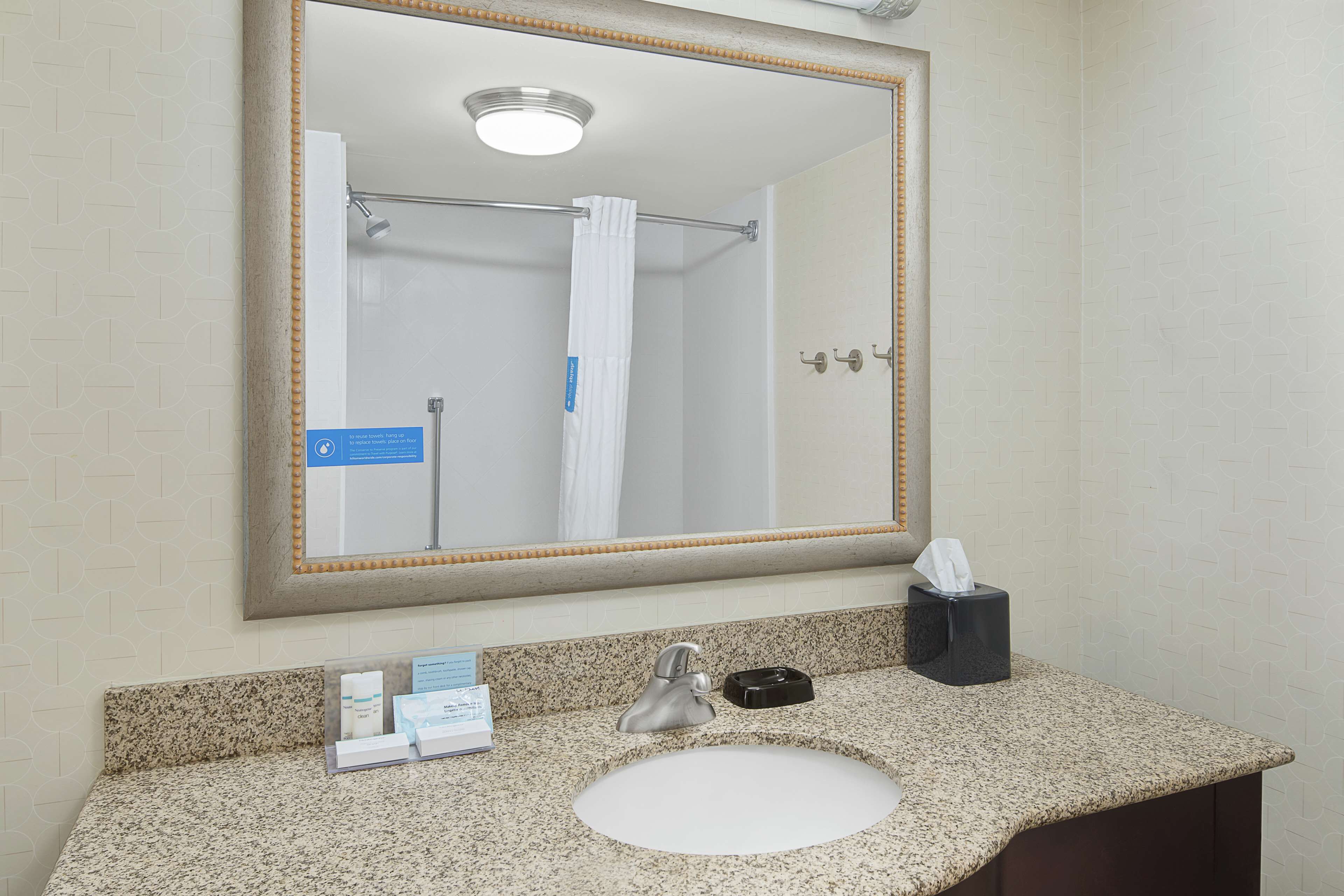 Un baño con un espejo grande, un lavabo y un perchero para toallas.