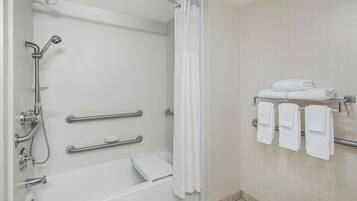 A modern bathroom with a walk-in shower, grab bars, a towel rack, and a white tiled wall.
