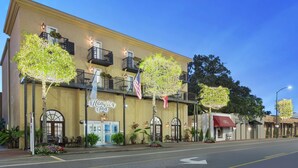 A hotel with a classic facade, outdoor seating, and decorative lighting.