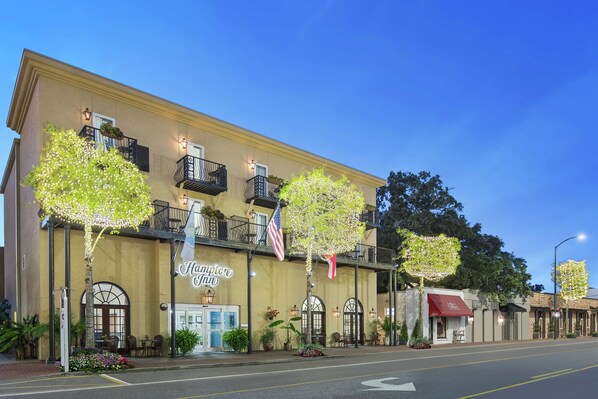 A hotel with a classic facade, outdoor seating, and decorative lighting.