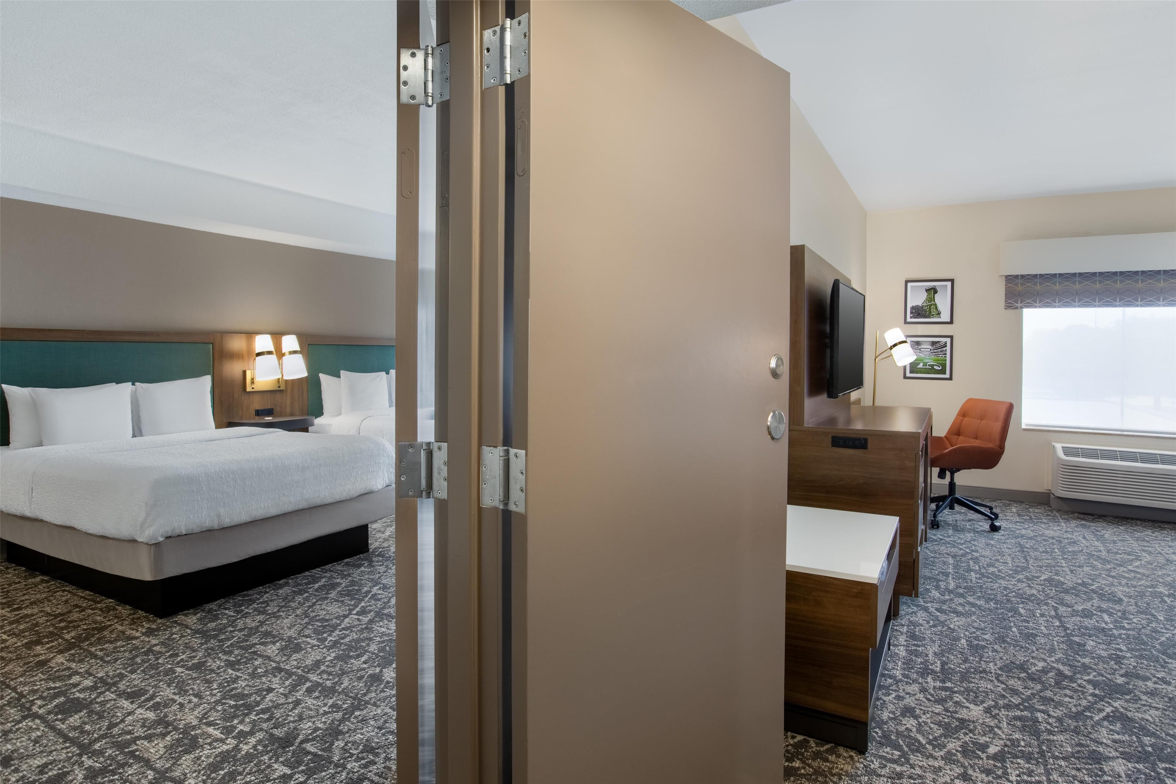 A hotel room with a bed, desk, chair, and a television.