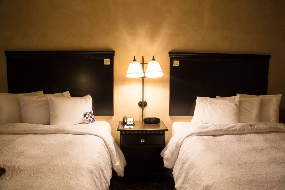 Une chambre d’hôtel avec deux lits, une table de chevet avec une lampe et un téléphone.