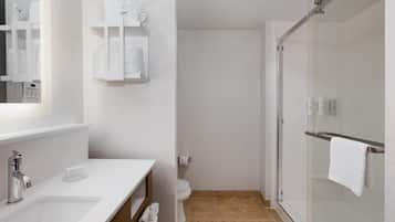 A modern bathroom with a white sink, mirror, and glass shower enclosure.