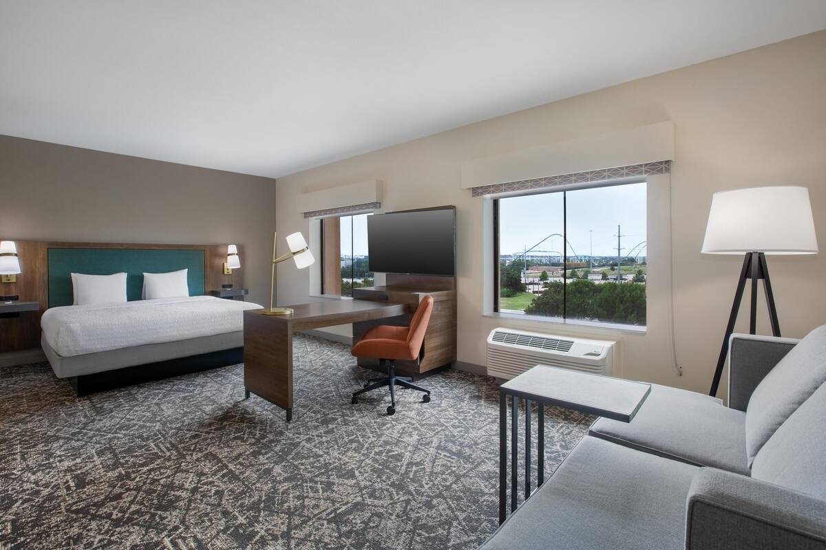 Une chambre d’hôtel avec un lit, un bureau, une chaise, une télévision et une vue sur un pont.