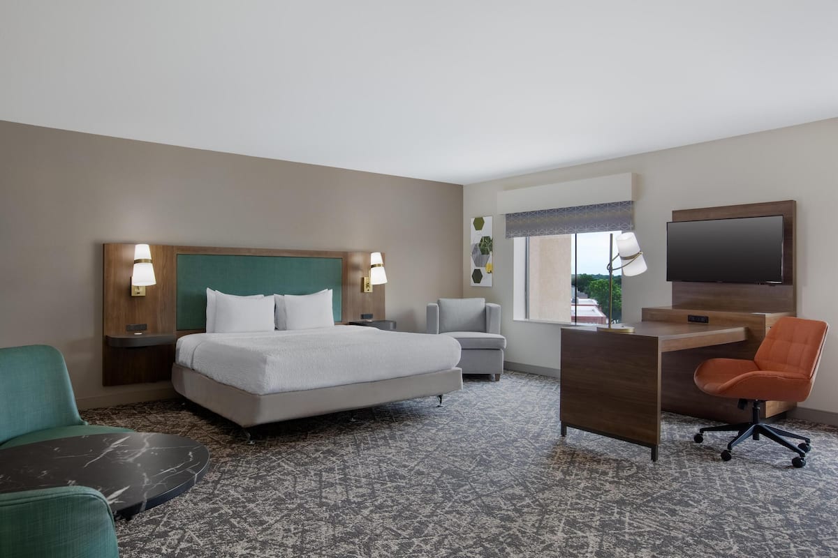 Une chambre d’hôtel avec un lit, un bureau, une chaise, une télévision et une fenêtre.