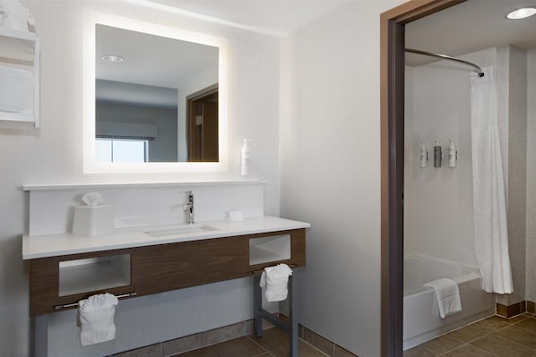 A modern bathroom with a white sink, mirror, and shower area.