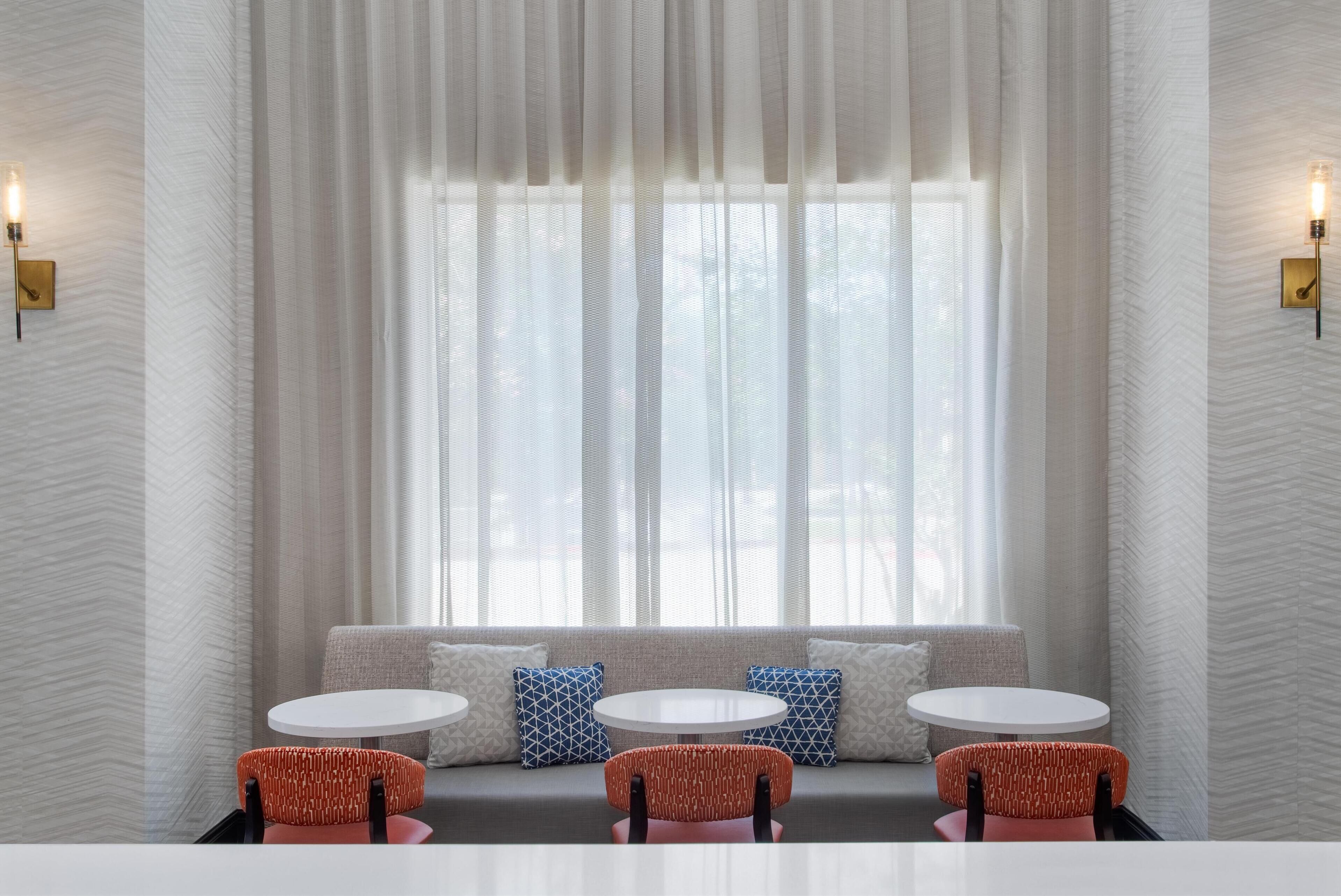 A modern interior with a seating area featuring a sofa and three round tables.