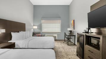 A hotel room with two beds, a desk, a television, and a microwave.