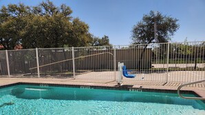 A clear swimming pool with a metal fence and a blue chair.
