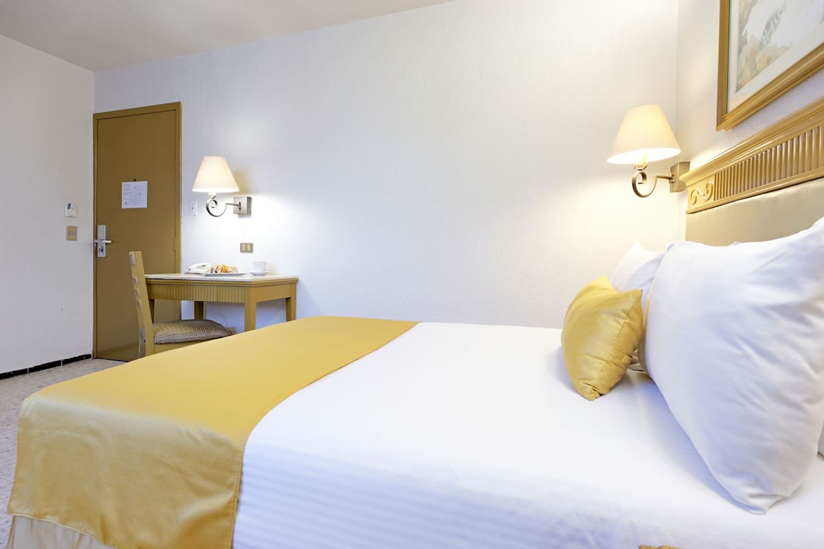 A hotel room with a bed, a desk, and a chair.