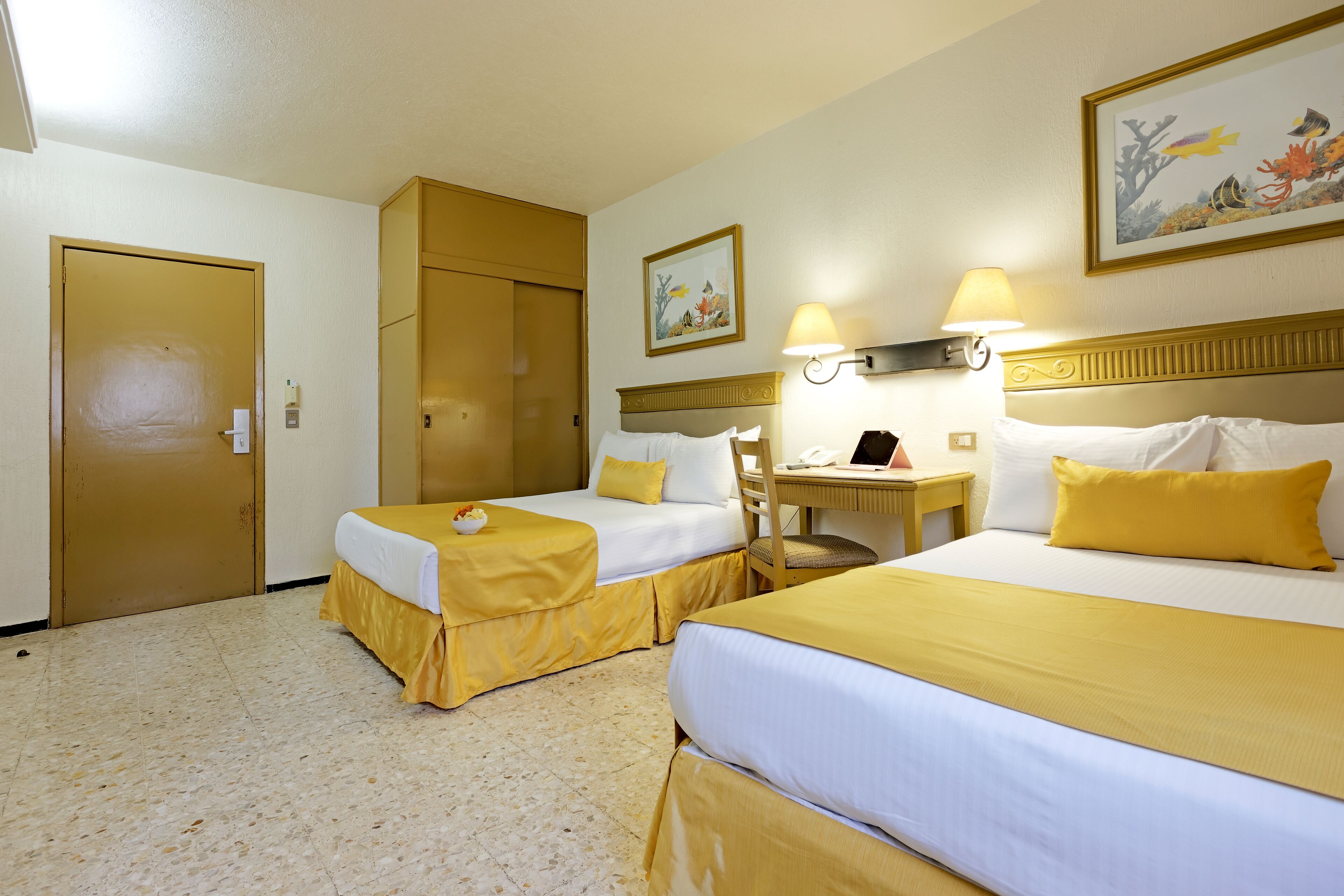 Une chambre d’hôtel avec deux lits, un bureau et une chaise.