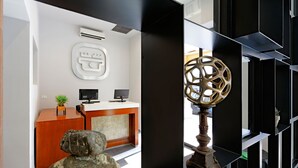 A reception area with a wooden desk, a computer, and a decorative sculpture.