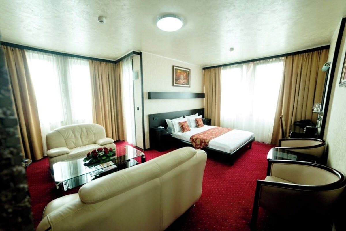 A hotel room with a bed, a sofa, a coffee table, and a desk.