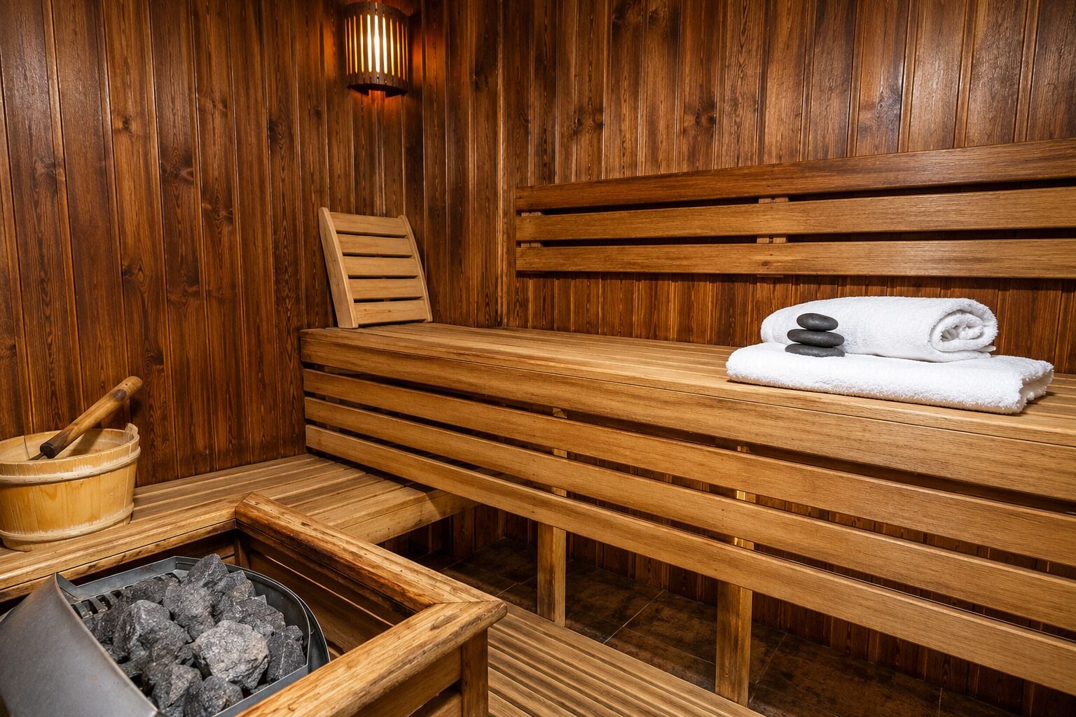 Eine Holzsauna mit Bänken, einem Eimer und einem Handtuch.