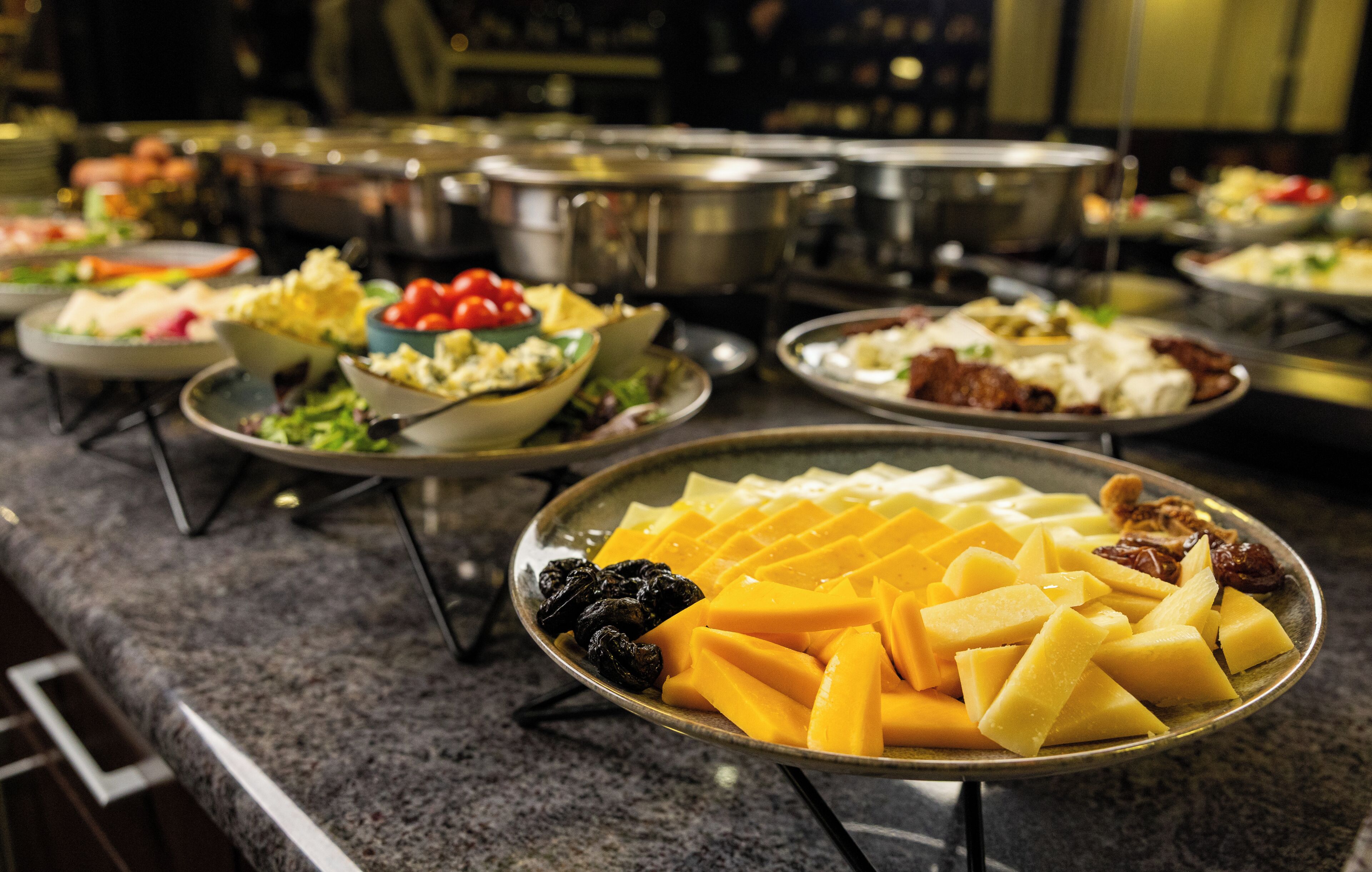 A buffet with various dishes including fruits and salads.