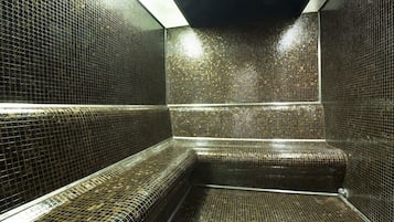 Relax in a serene sauna room with a unique tile design and comfortable seating.