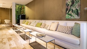 A modern living room with a white sofa, multiple cushions, and a coffee table. - CasaCalma Hotel (Buenos Aires)