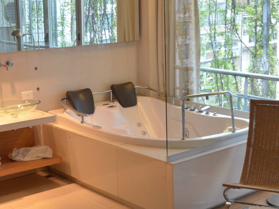 Un baño moderno con una bañera grande, cabina de ducha con mampara de vidrio y suelo de madera.
